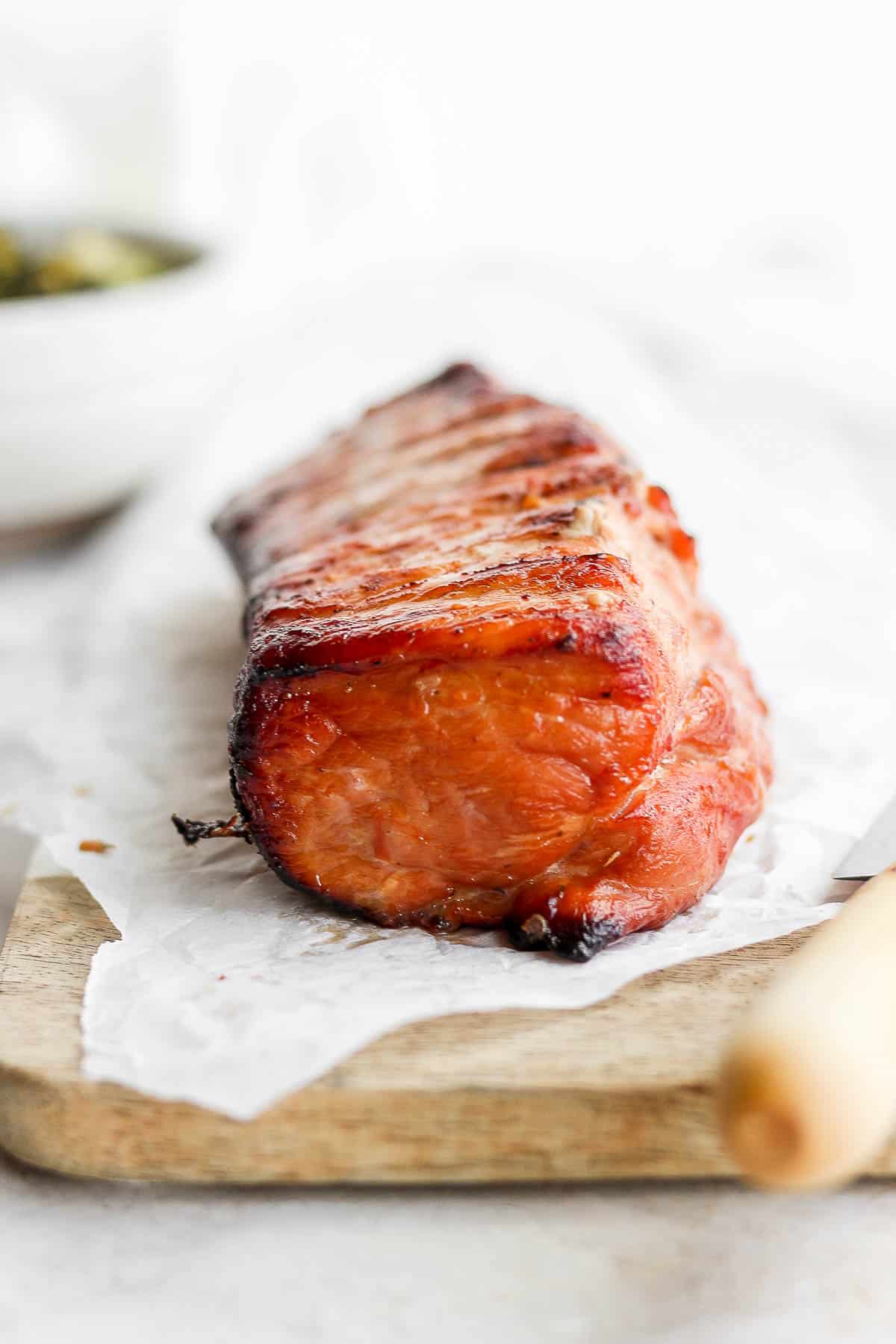 A smoked pork loin on a piece of parchment showing the charred end.