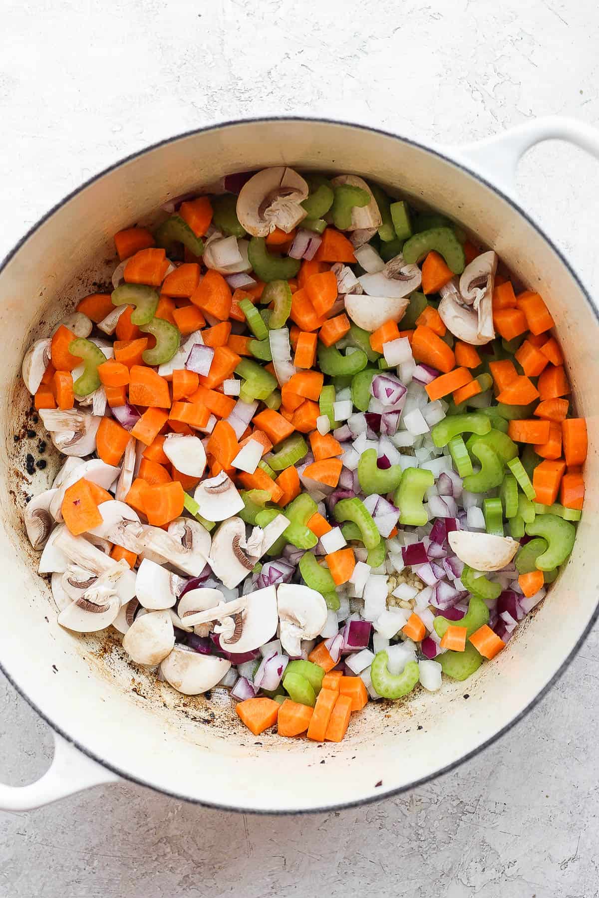 A dutch oven with all the cut-up vegetables in it.