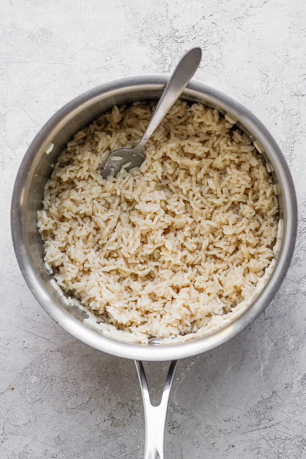 Coconut rice in a saucepan with a fork.