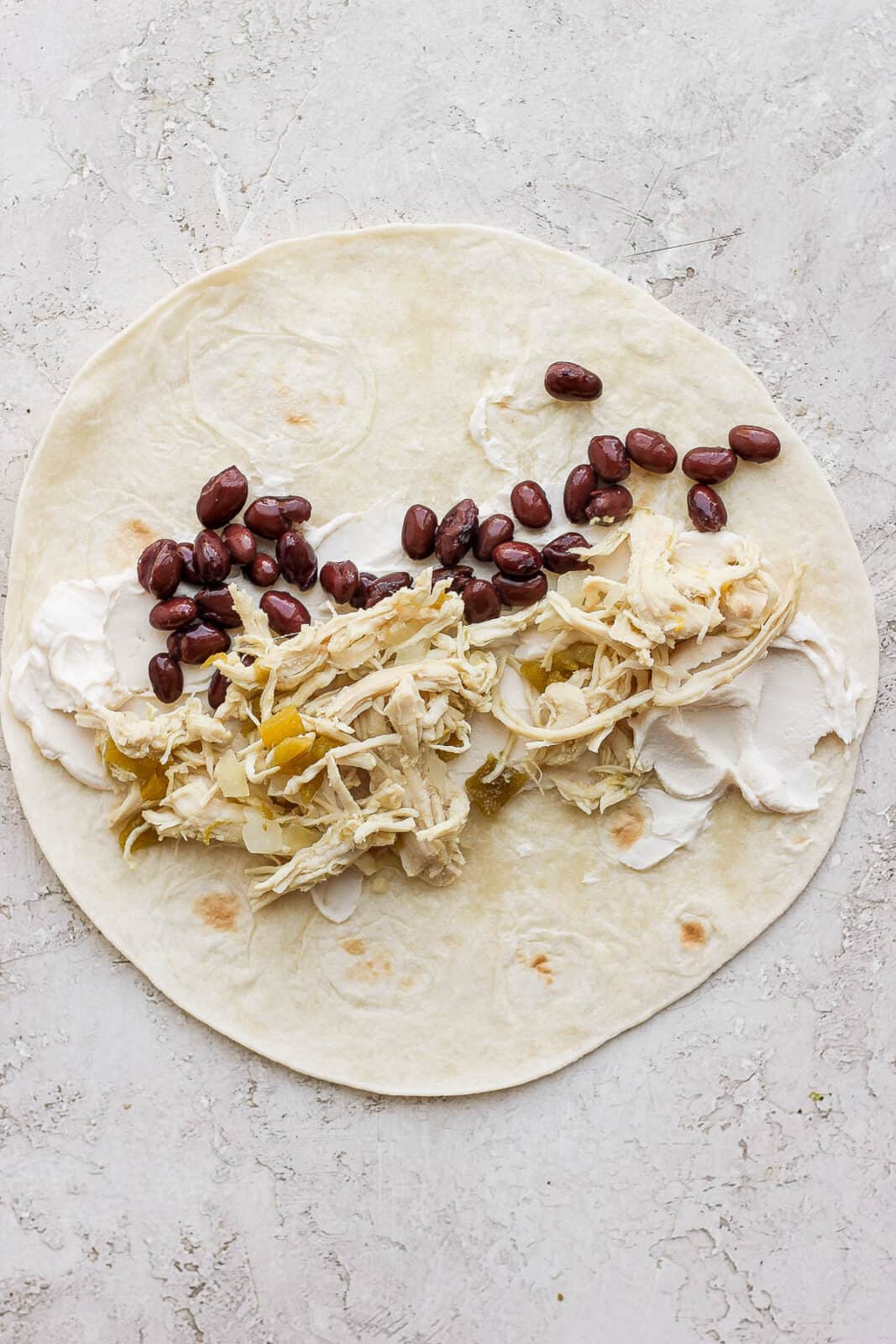 A tortilla with cream cheese, black beans, and chicken mixture.