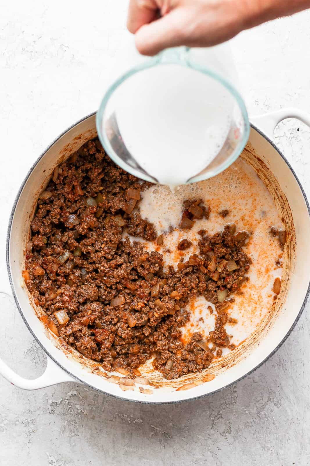 Almond milk being poured into the ground beef mixture.