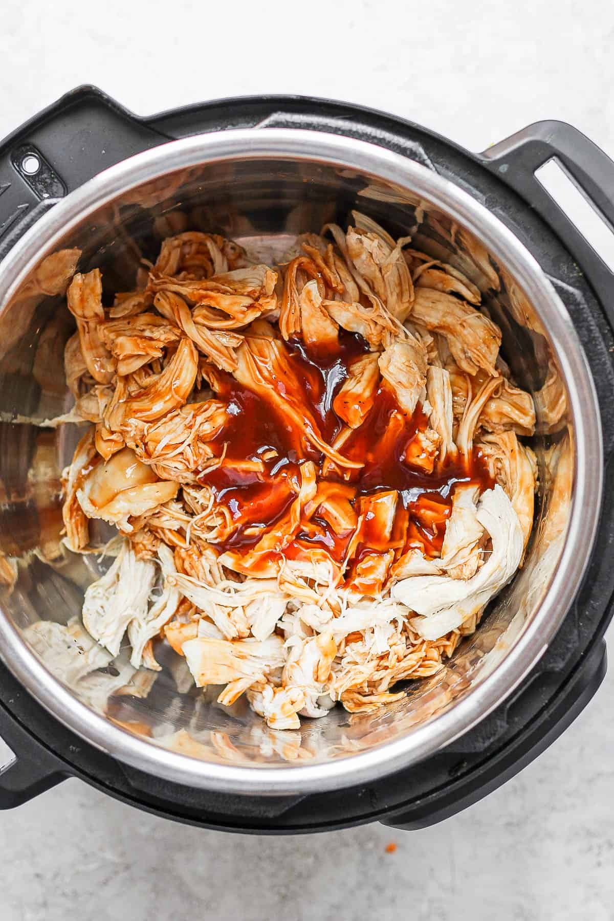 Shredded chicken in an instant pot with some bbq sauce added.