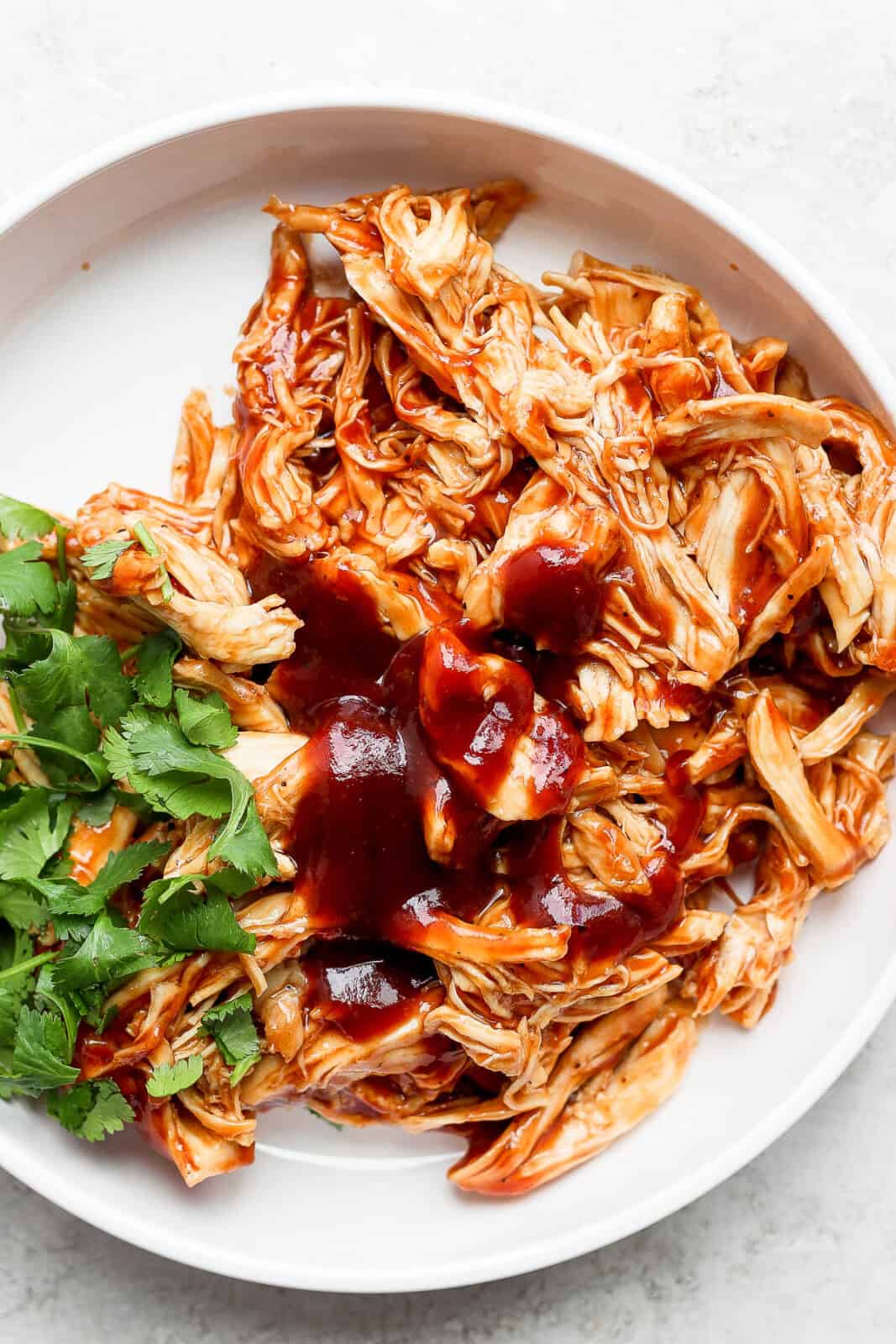 Instant pot bbq chicken on a plate with cilantro.
