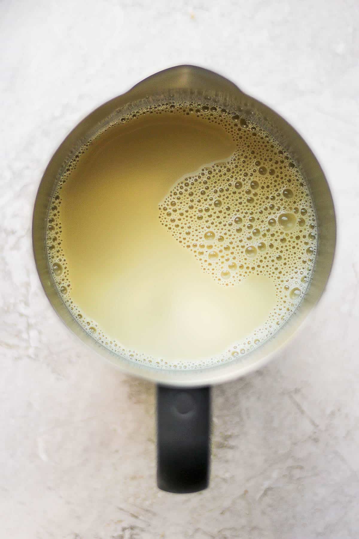 Pistachio milk, vanilla extract, and maple syrup in a frother.