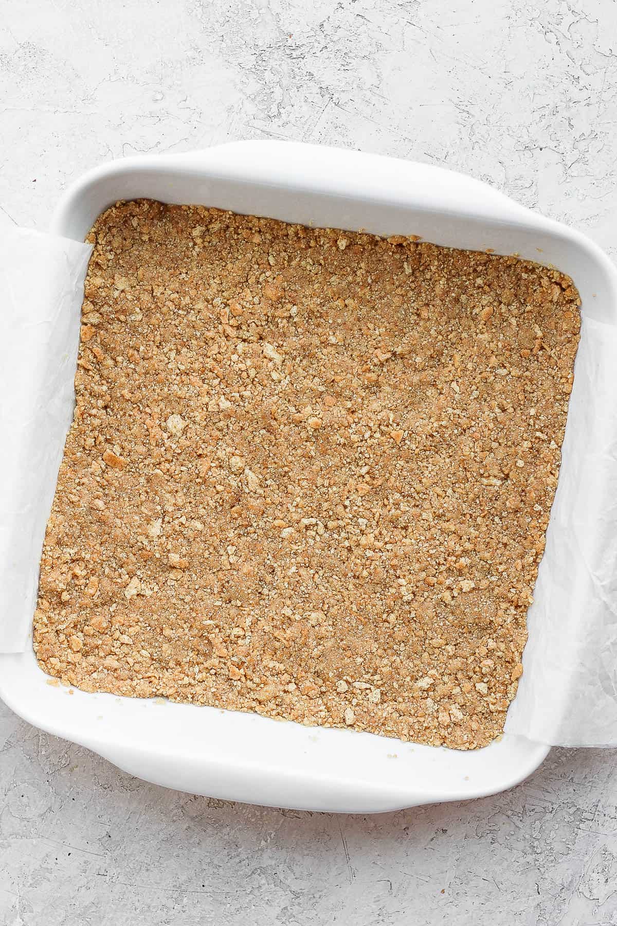 Graham cracker crust in a parchment-lined pan.