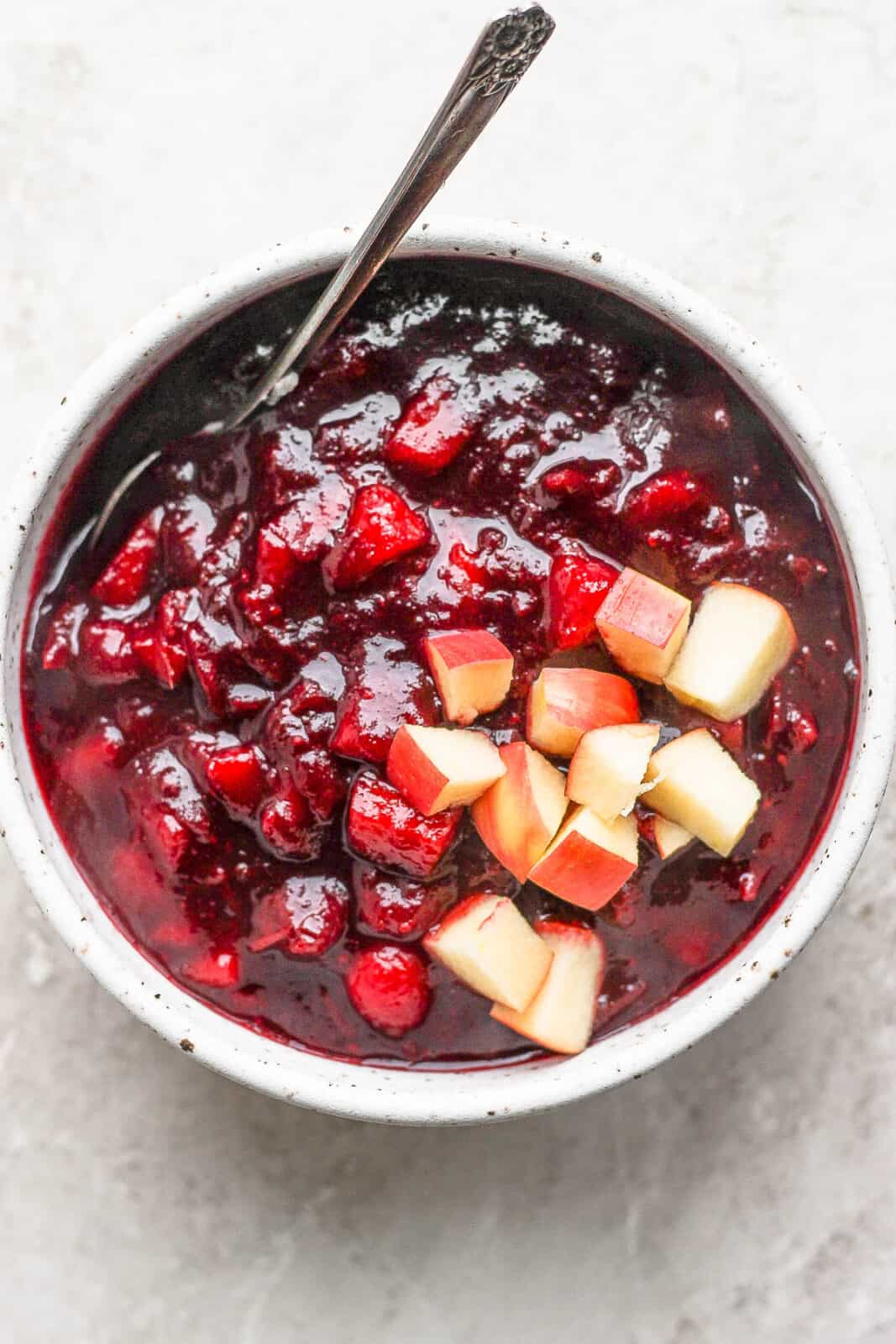 Apple cranberry sauce in a bowl with a spoon.