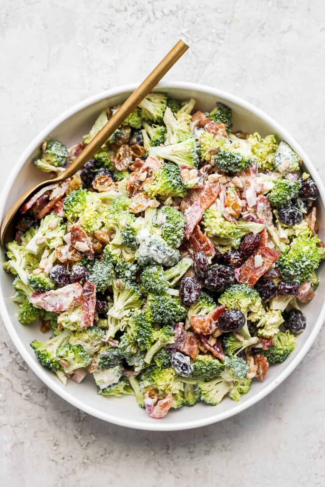 A large bowl of broccoli bacon salad with a spoon.