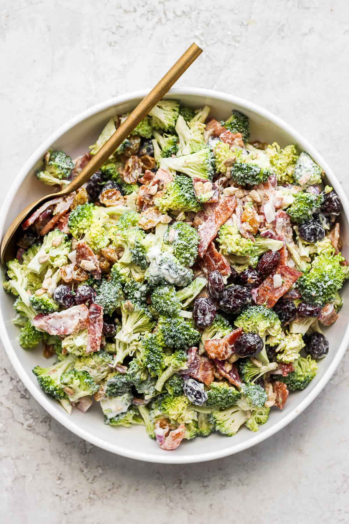 A large bowl of broccoli bacon salad with a spoon.