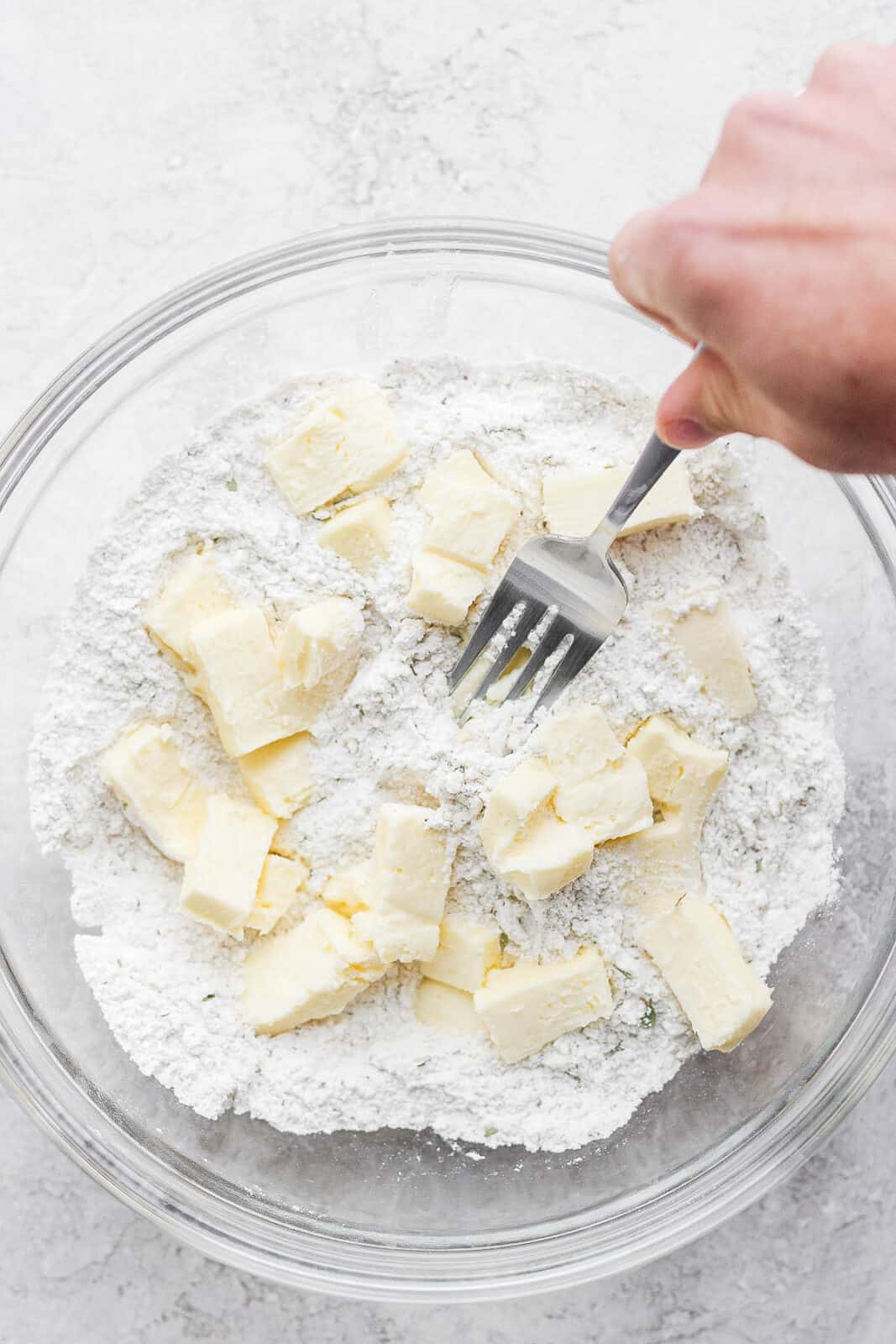 A fork mixing butter into the dry ingredients for gluten free biscuits.