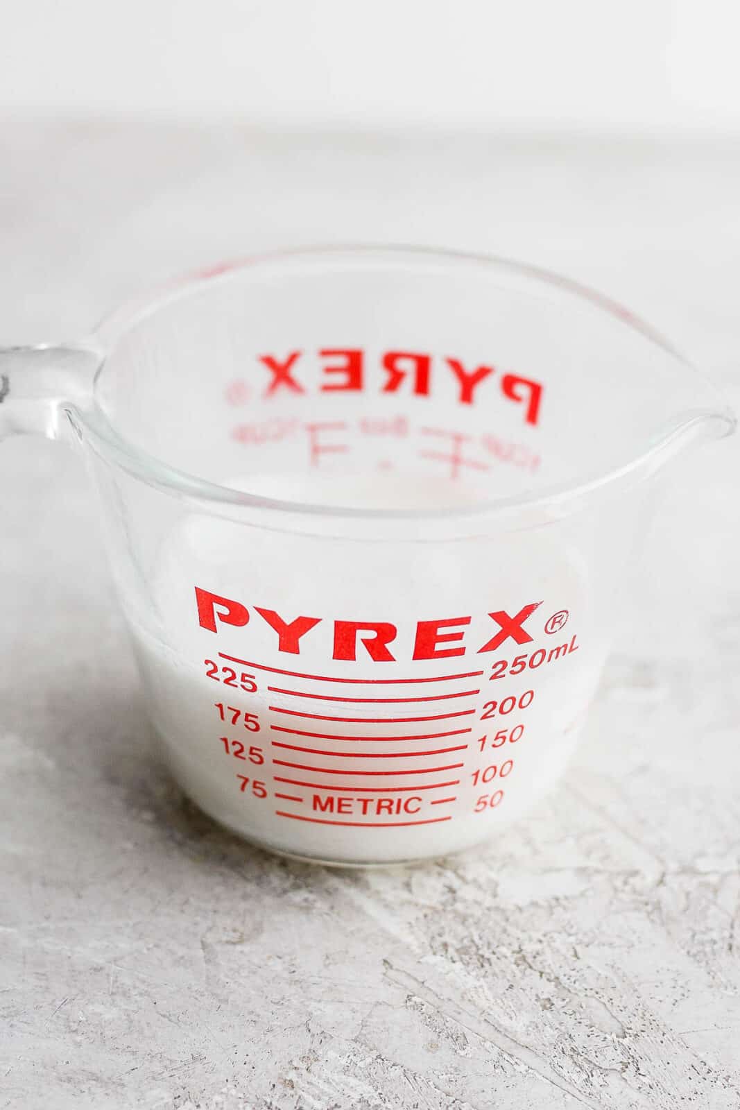 A measuring cup of almond milk mixed with lemon juice.