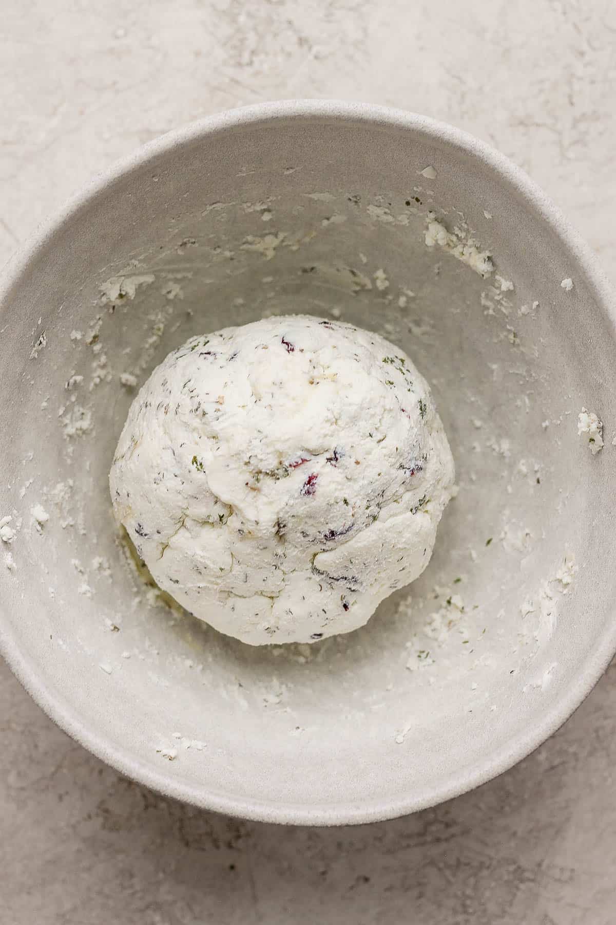 The goat cheese ball formed in a bowl.