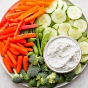 A small dish of vegetable dip on a plate of fresh vegetables.