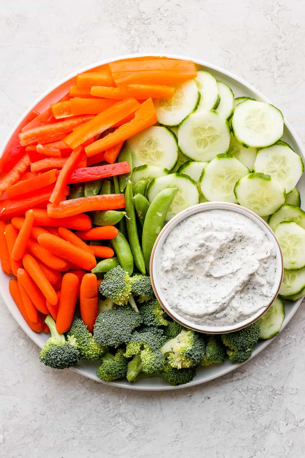 A small dish of healthy veggie dip on a plate of fresh veggies.
