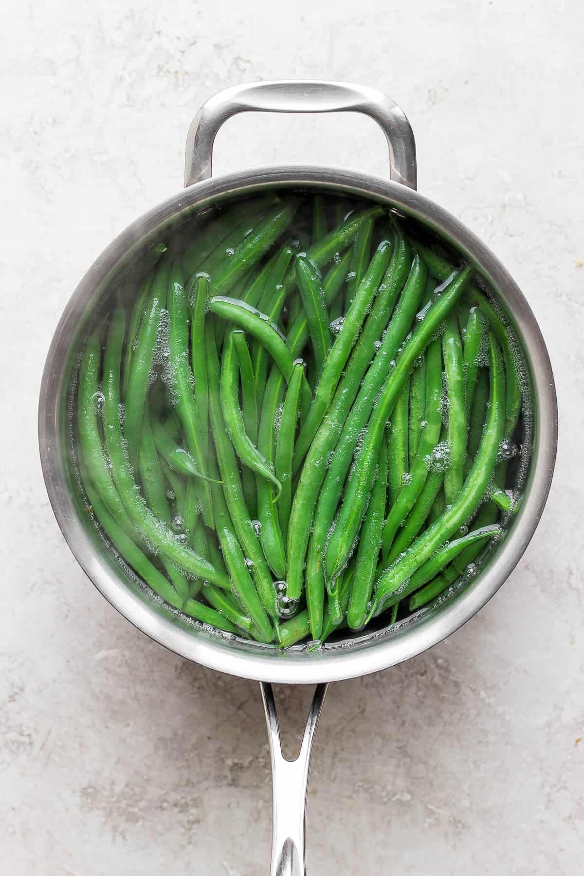 Green beans being blanched in a pot of steaming water. 