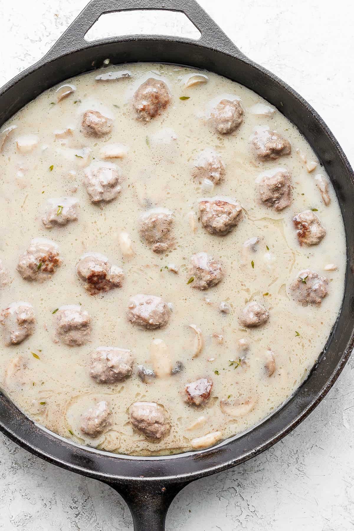 Meatballs and cream of mushroom soup in a cast iron skillet.