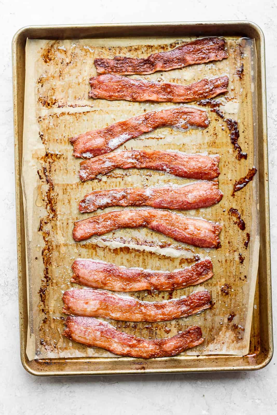 Bacon on a parchment-lined baking sheet after baking.