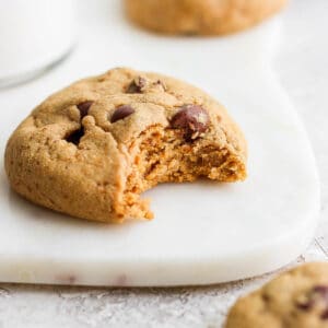 A paleo chocolate chip cookie with a bite taken out of it.