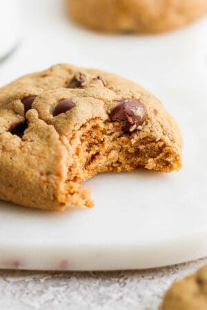 A paleo chocolate chip cookie with a bite taken out of it.