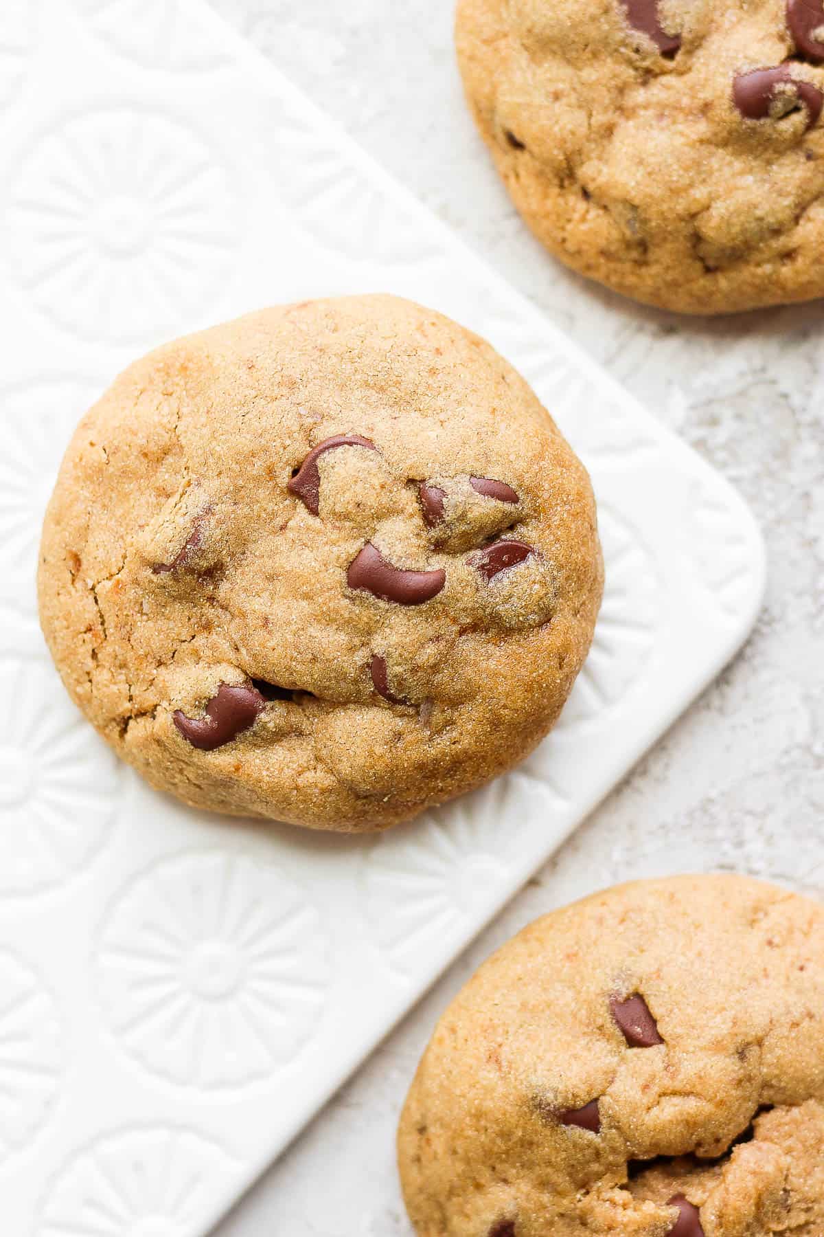 A paleo chocolate chip cookie on a decorative board.