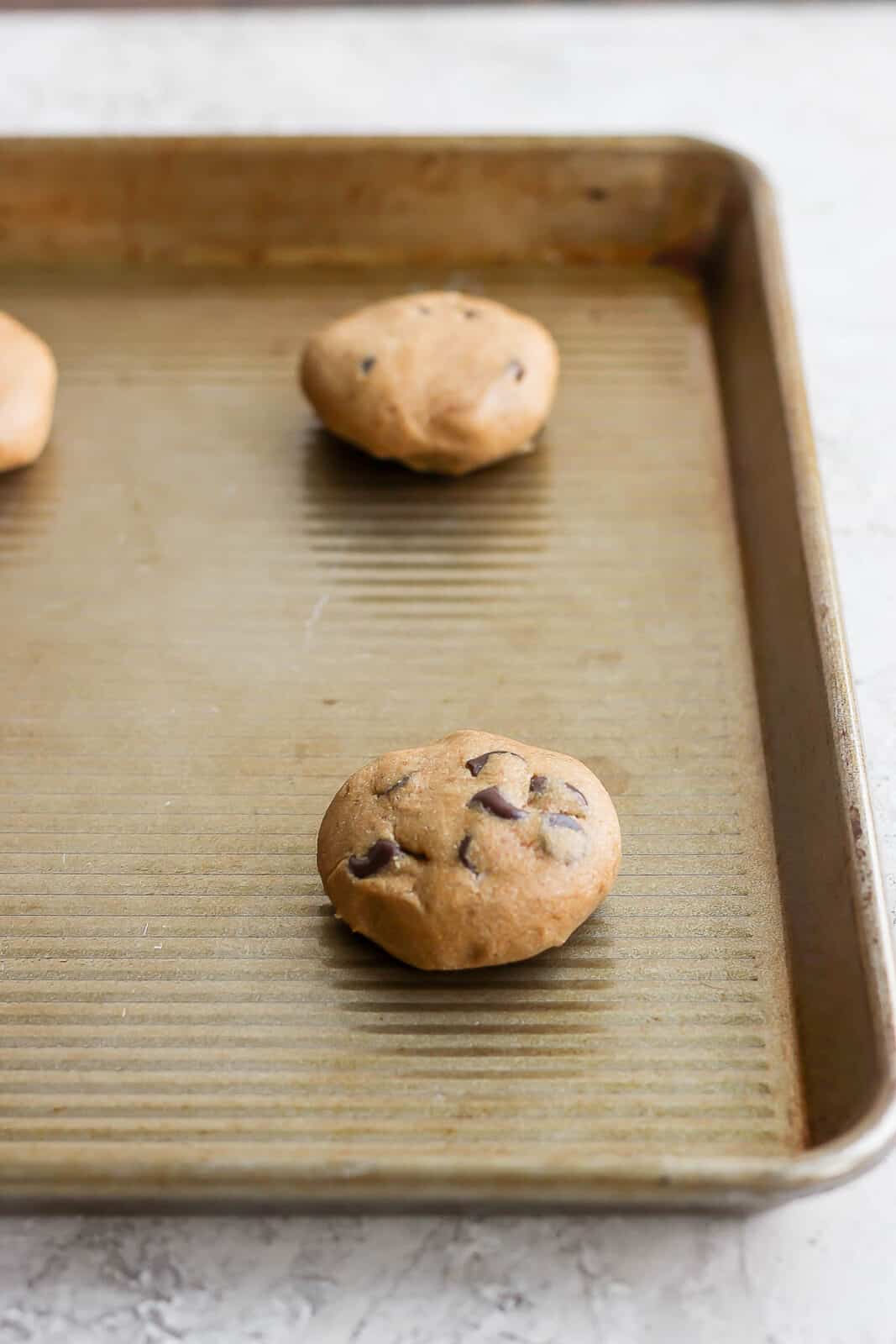 Two tablespoons of paleo chocolate chip cookie dough on a baking sheet.