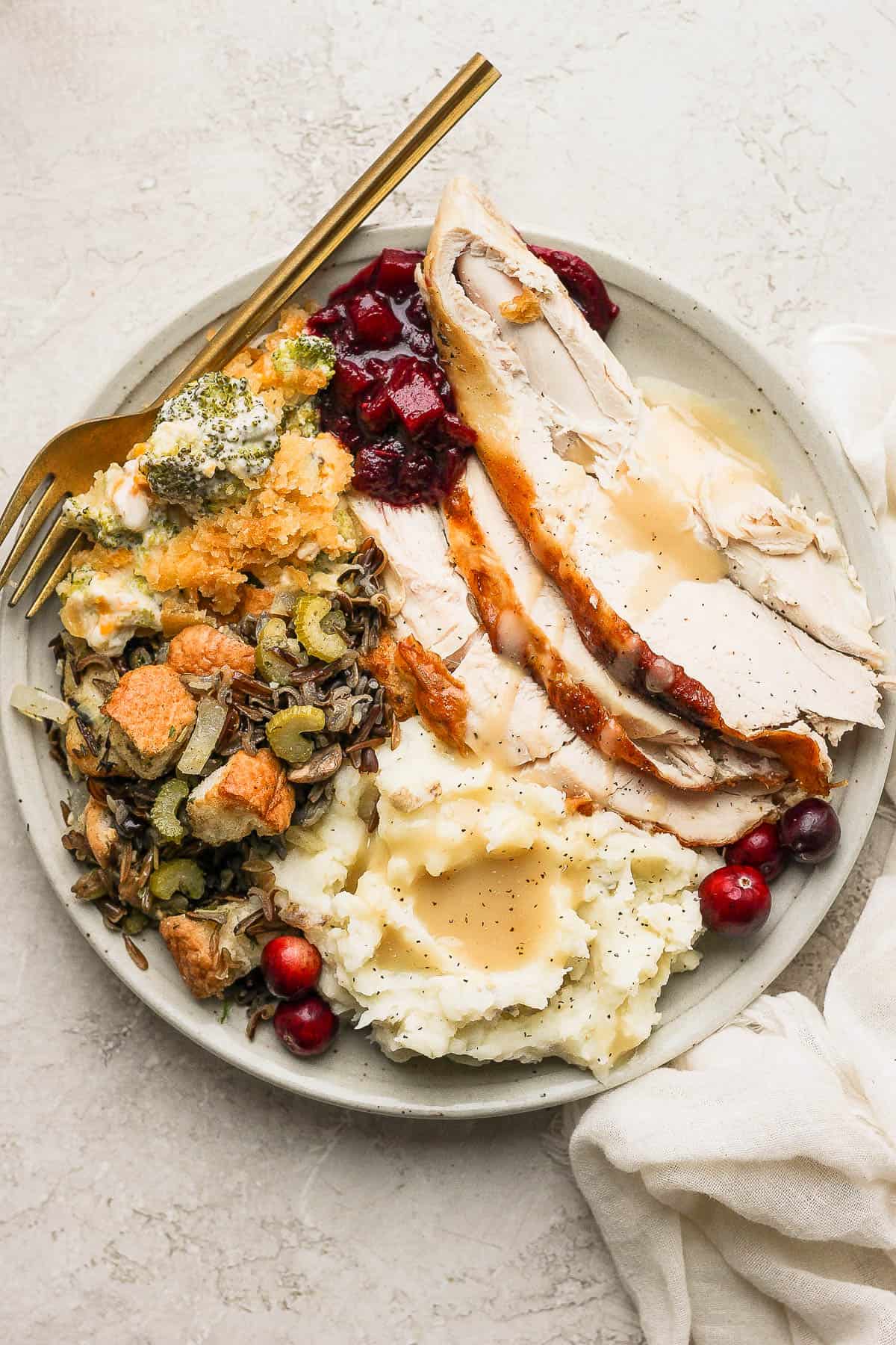 A plate of turkey, cranberry sauce, stuffing and broccoli casserole. 