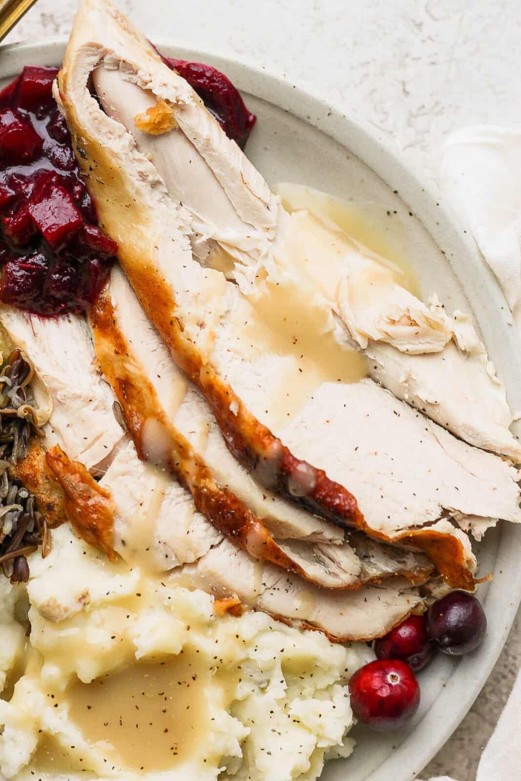 A plate with sliced turkey and gravy (close-up).