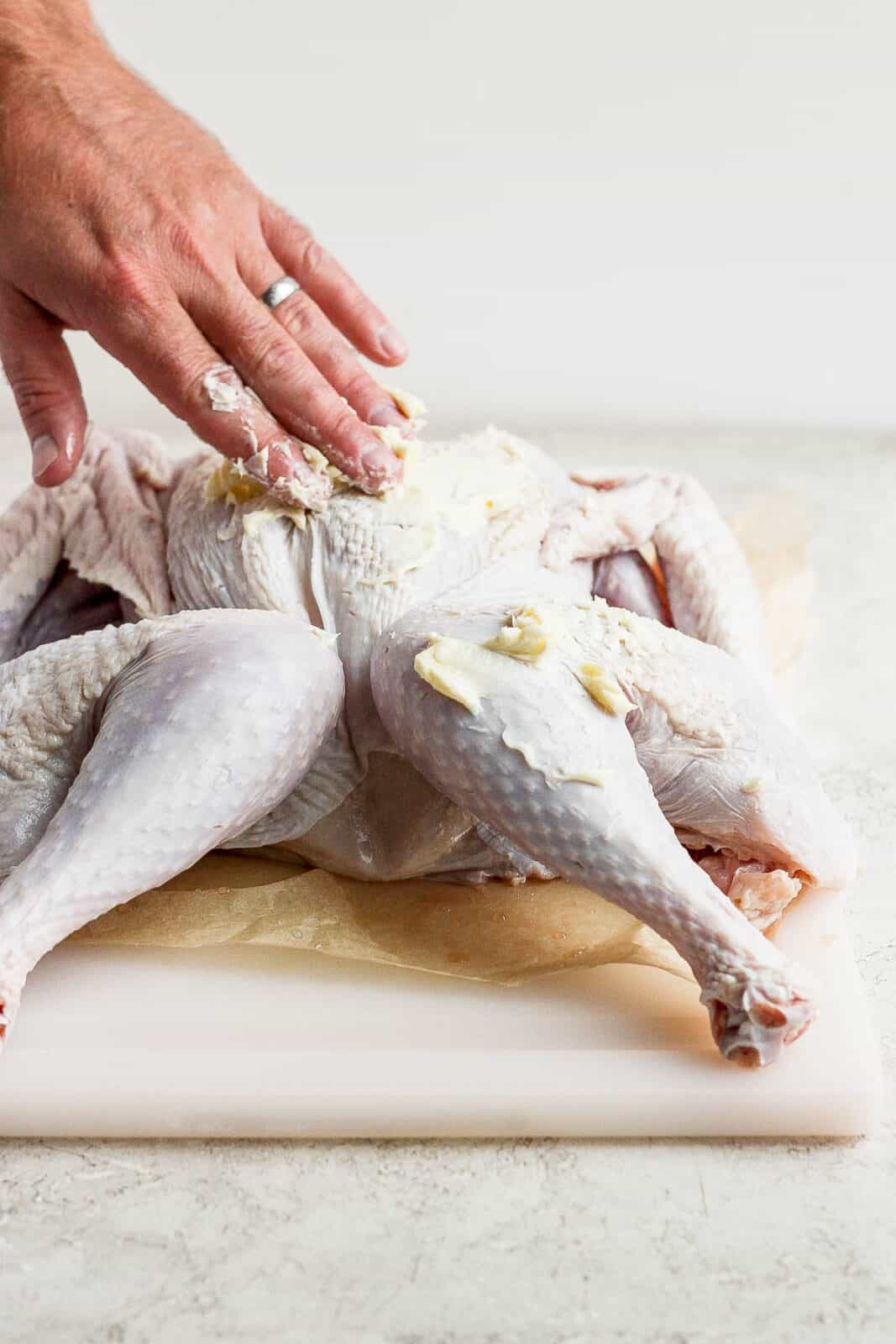 Someone rubbing softened butter on a turkey. 