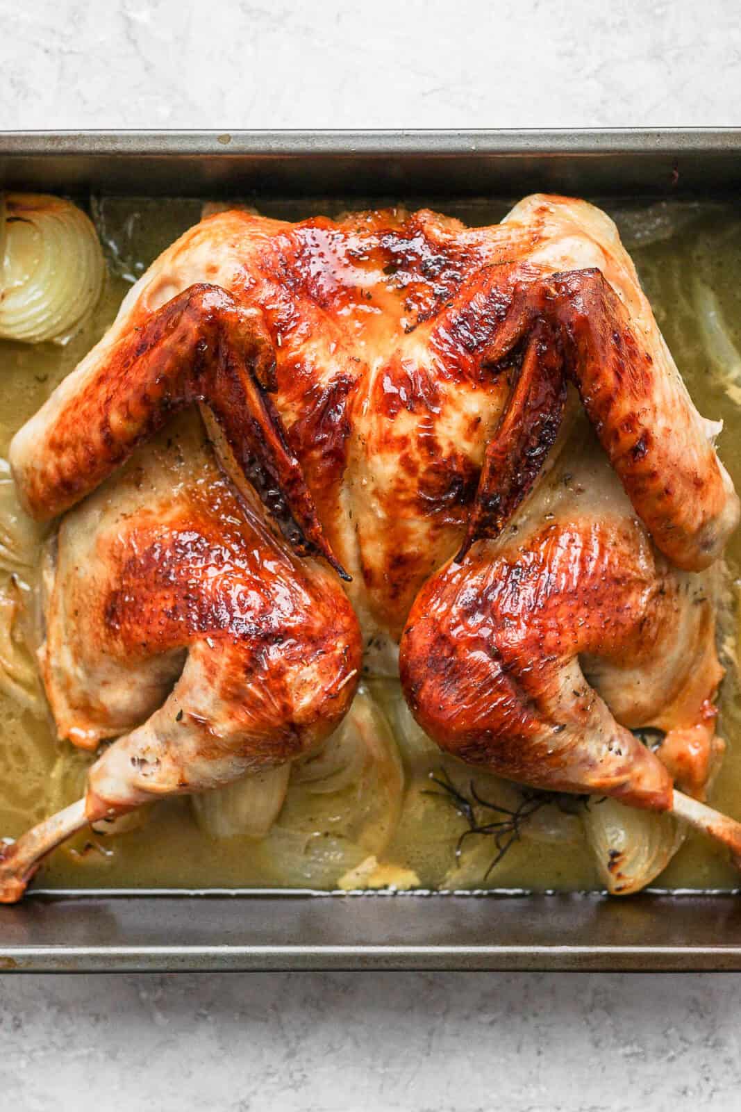 A spatchcock turkey roasted sitting in a roasting pan. 