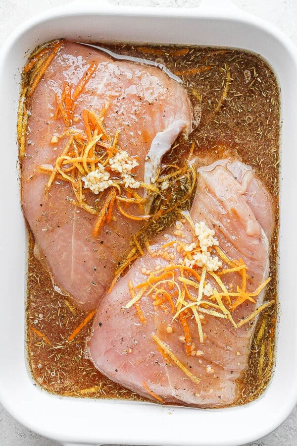 Pan with two turkey tenderloins covered in a turkey marinade.