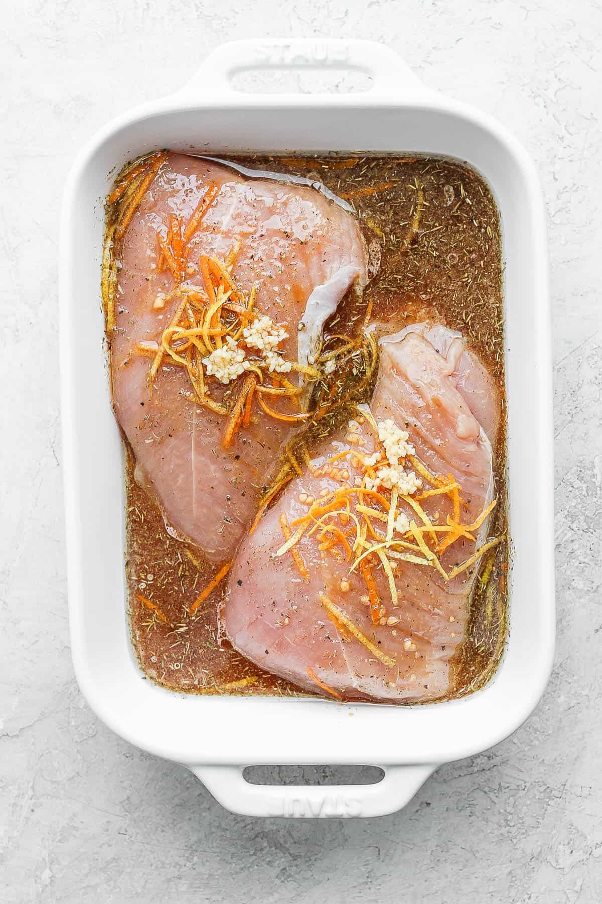 A turkey tenderloin in the turkey marinade in a shallow dish.