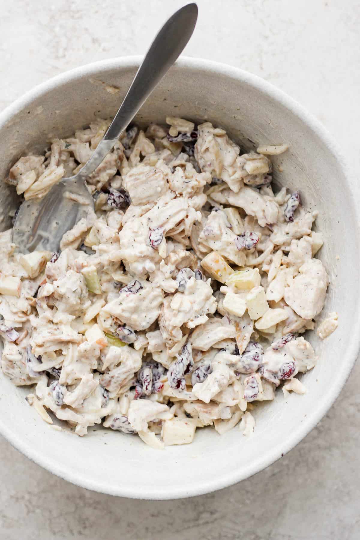 Turkey salad after mixing in a large bowl with a spoon.