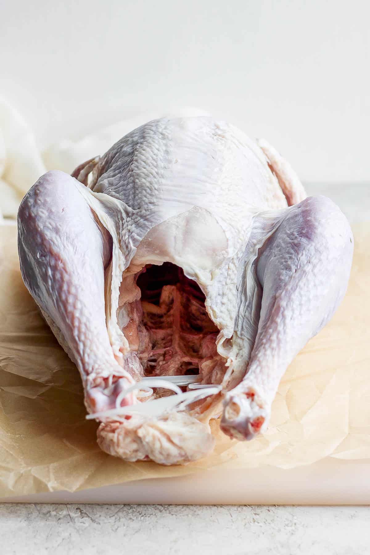 A raw turkey on parchment paper.