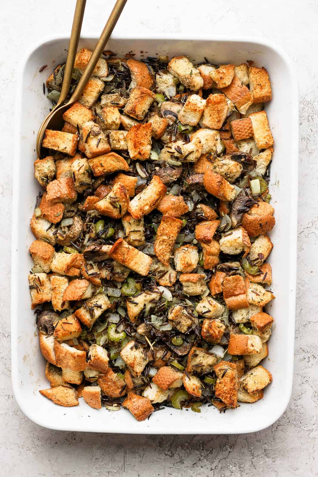 Wild rice stuffing in a baking dish with spoons.