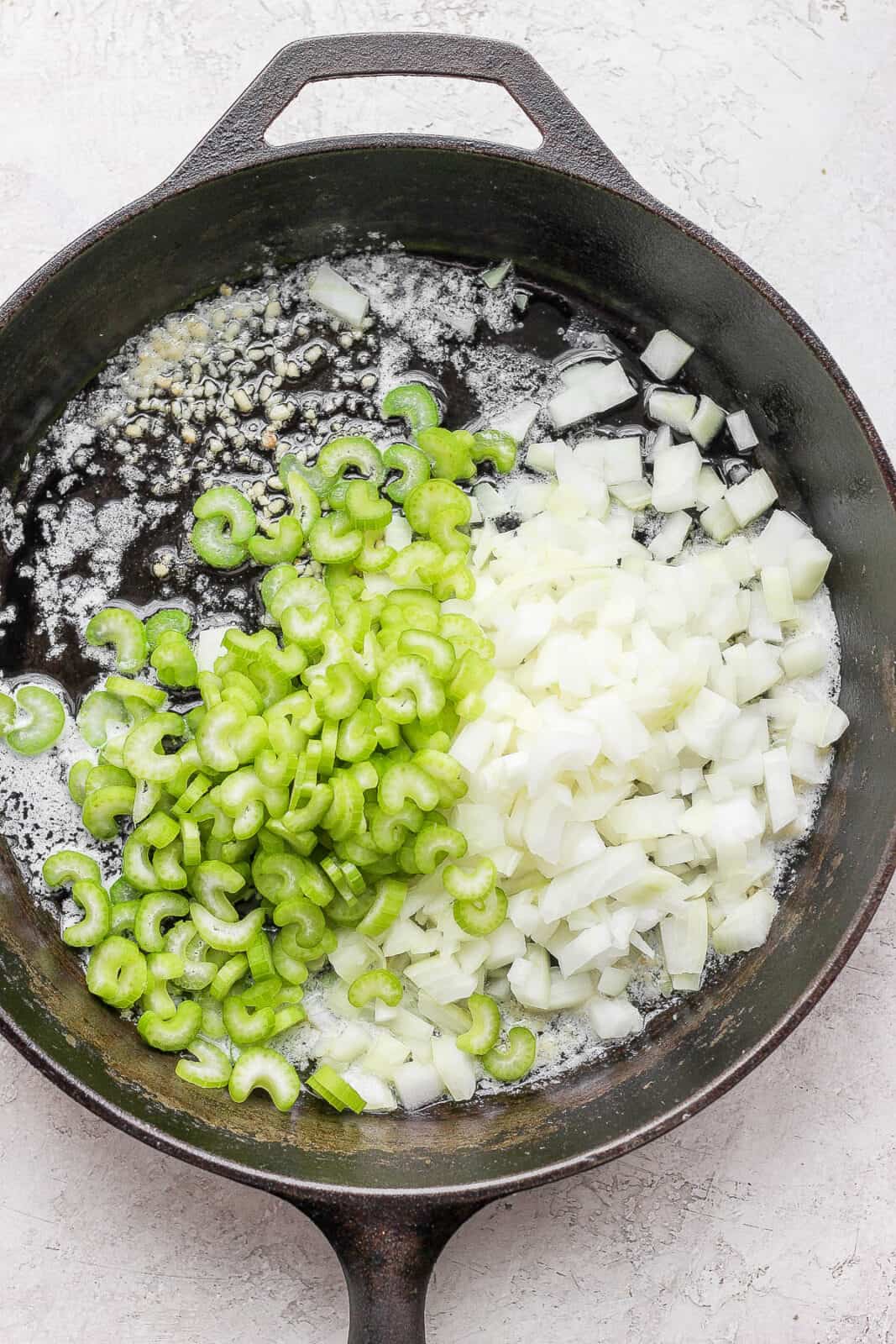 Garlic, onion, and celery in a cast iron skillet.