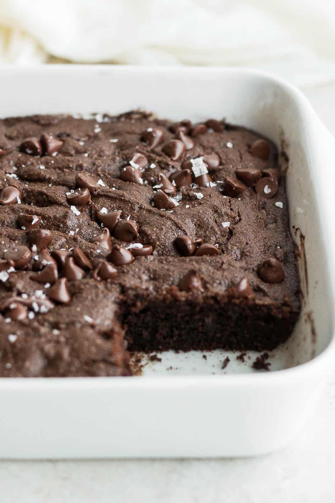 Side view of a pan of almond flour brownies with one piece taken out. 