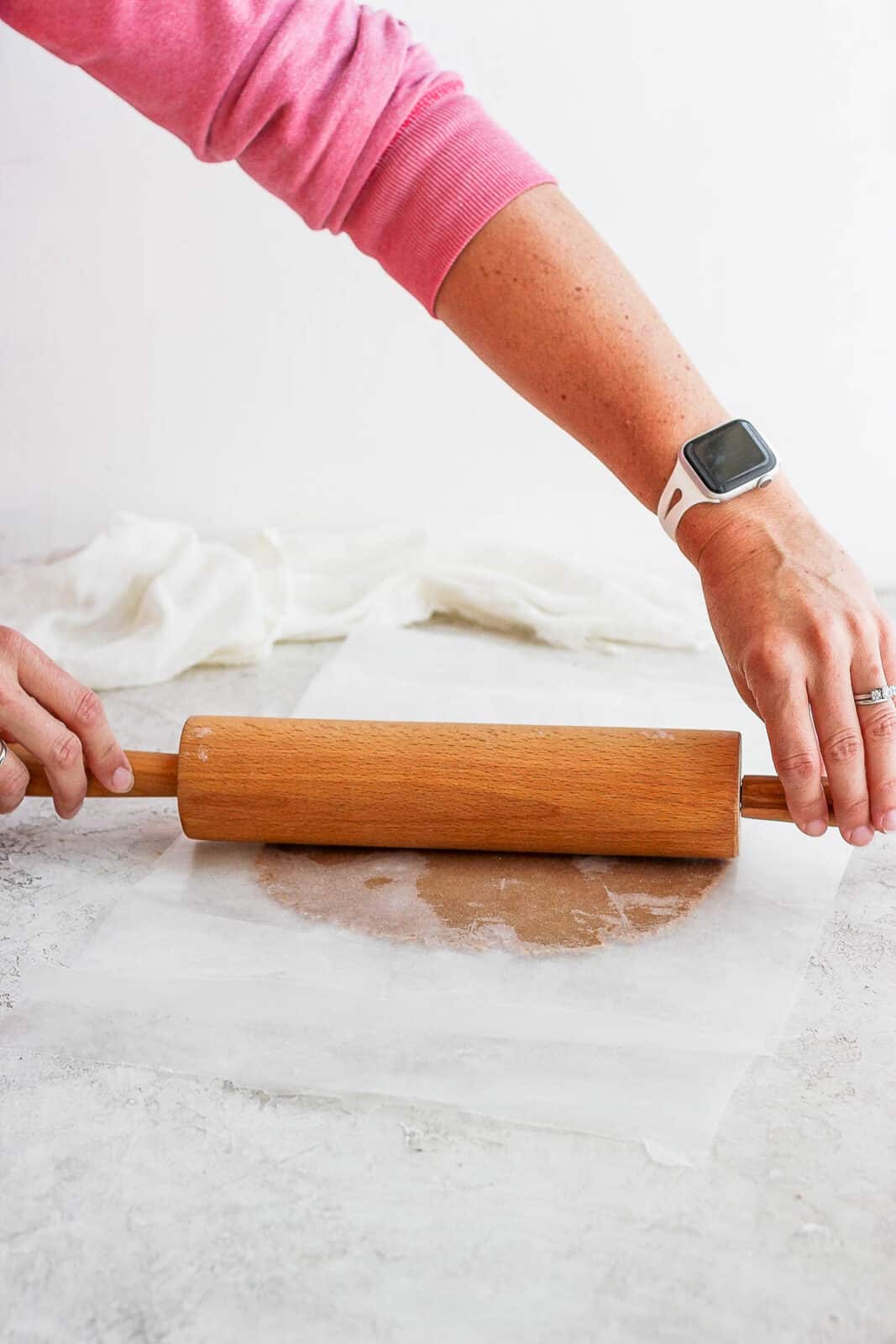 Almond flour cookie dough being rolled out by a rolling pin.