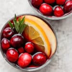 A cup of Christmas Sangria with an orange slice, cranberries and fresh rosemary.