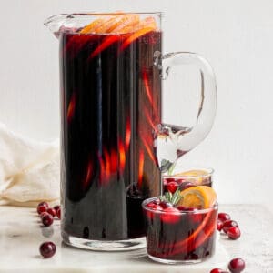 A pitcher of Christmas Sangria with a smaller glass beside it.