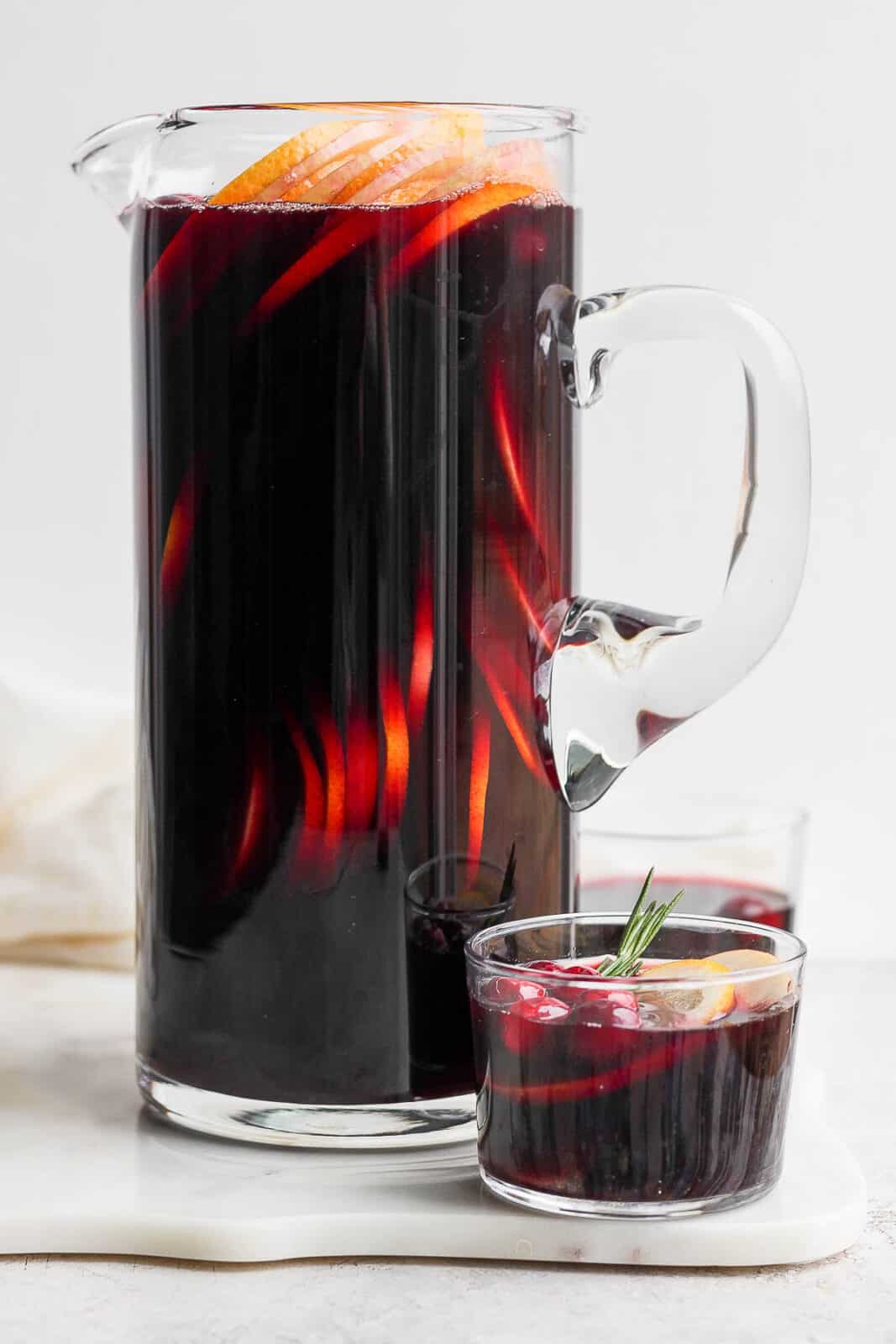A glass and pitcher of Christmas sangria.