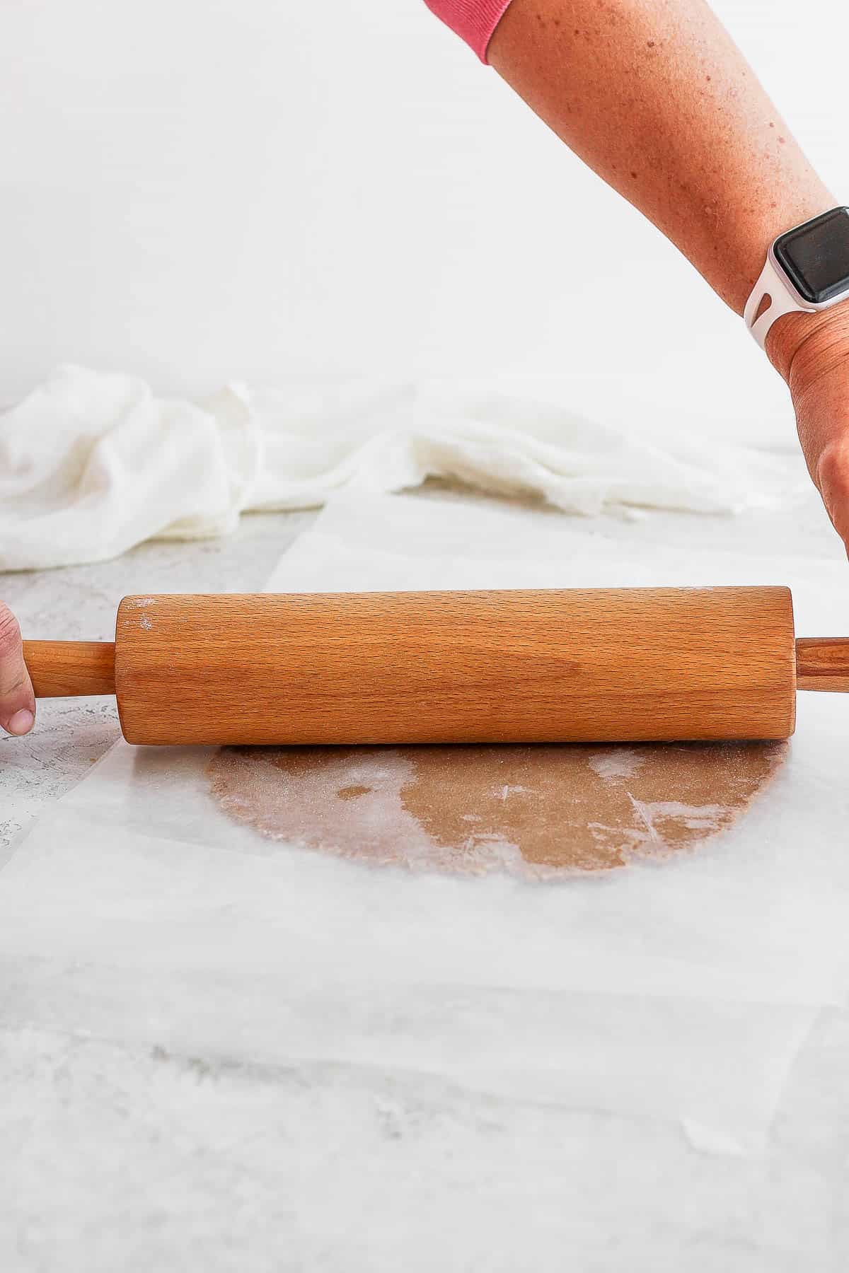 Gluten free sugar cookie dough being rolled out with a rolling pin.