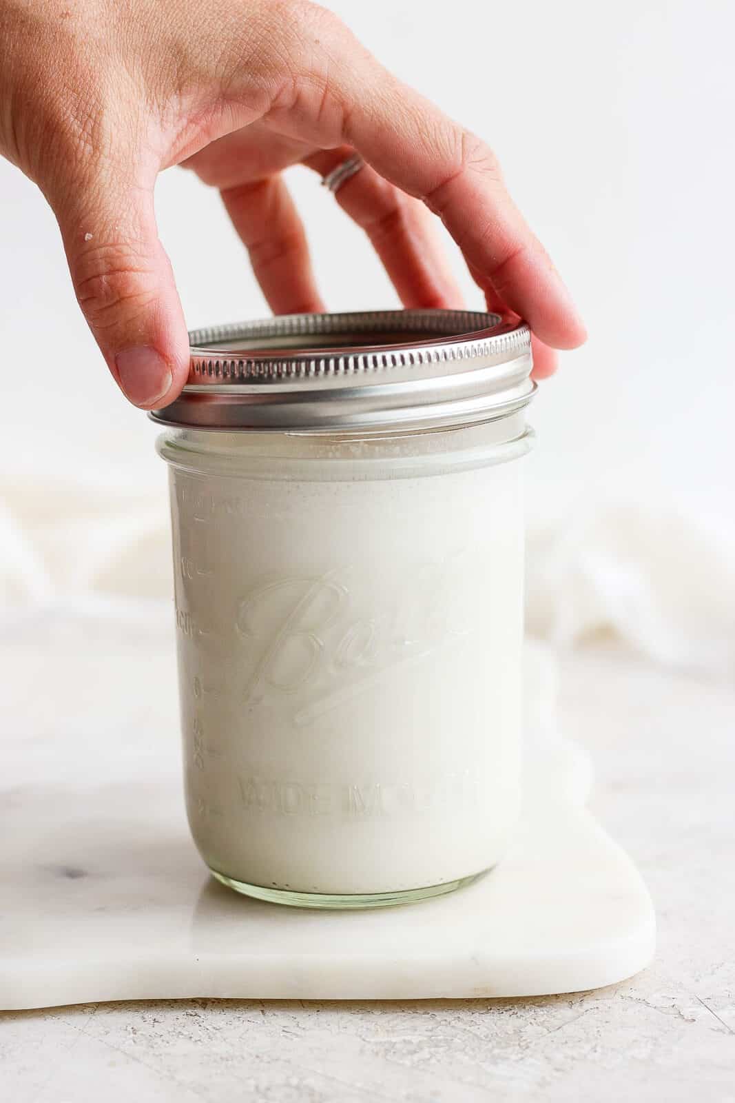 Cashew milk in a mason jar with the lid being put on.