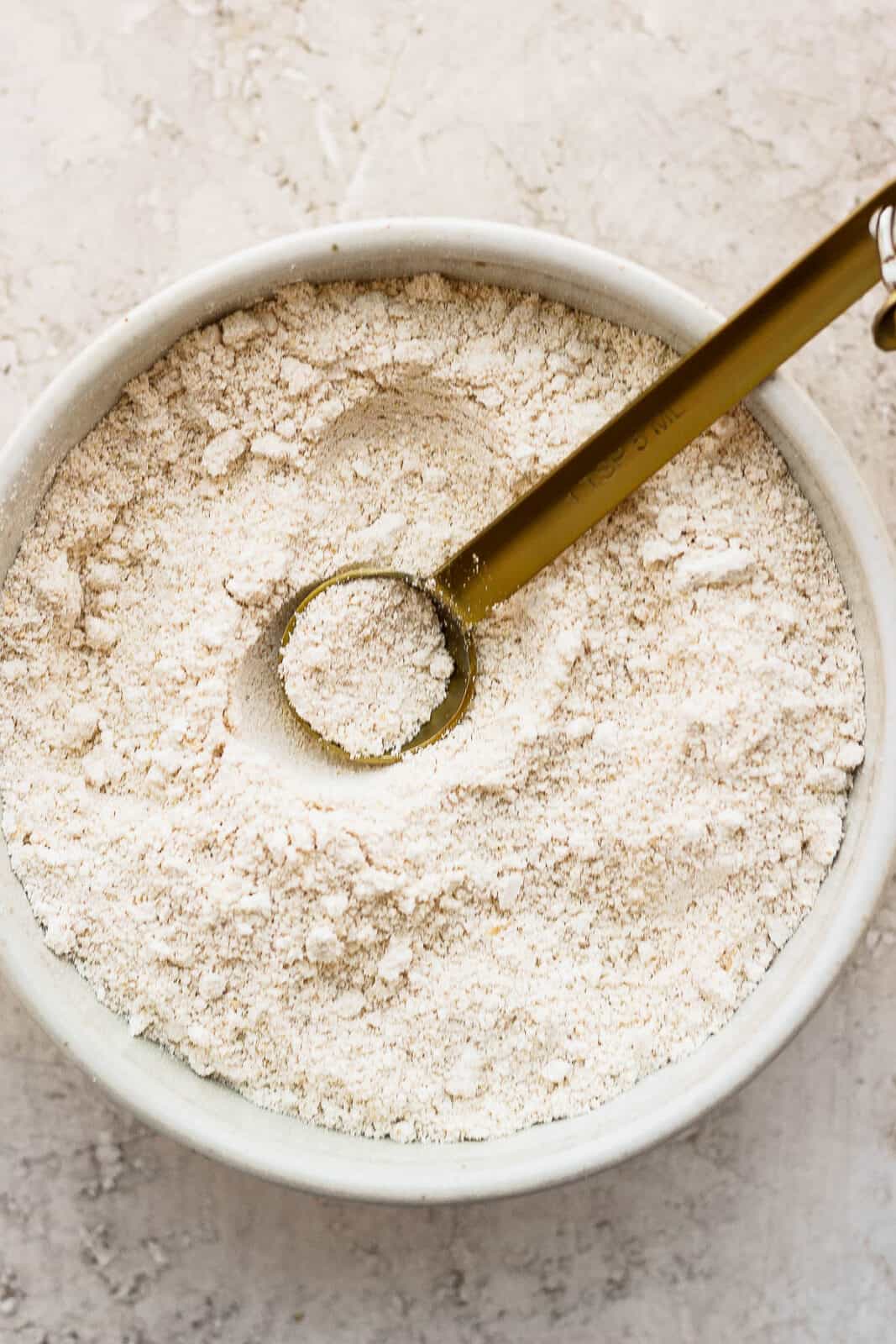 Oat flour in a bowl with a measuring spoon.