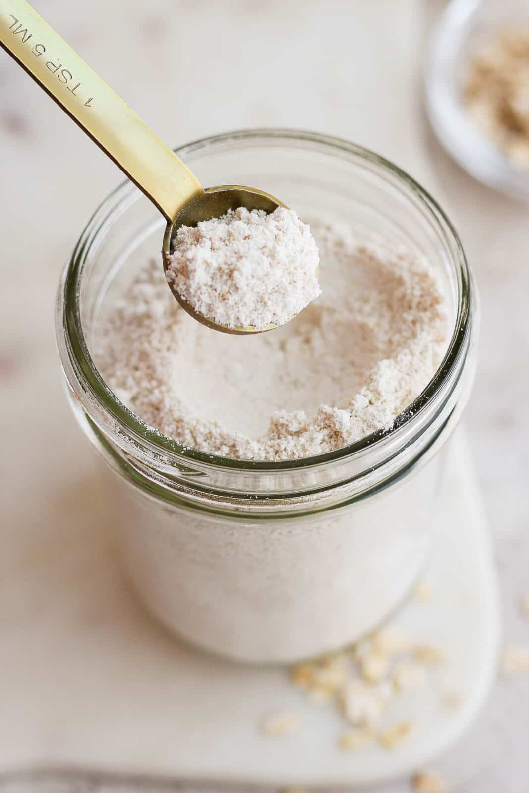 Oat flour in a mason jar with a measuring spoon.