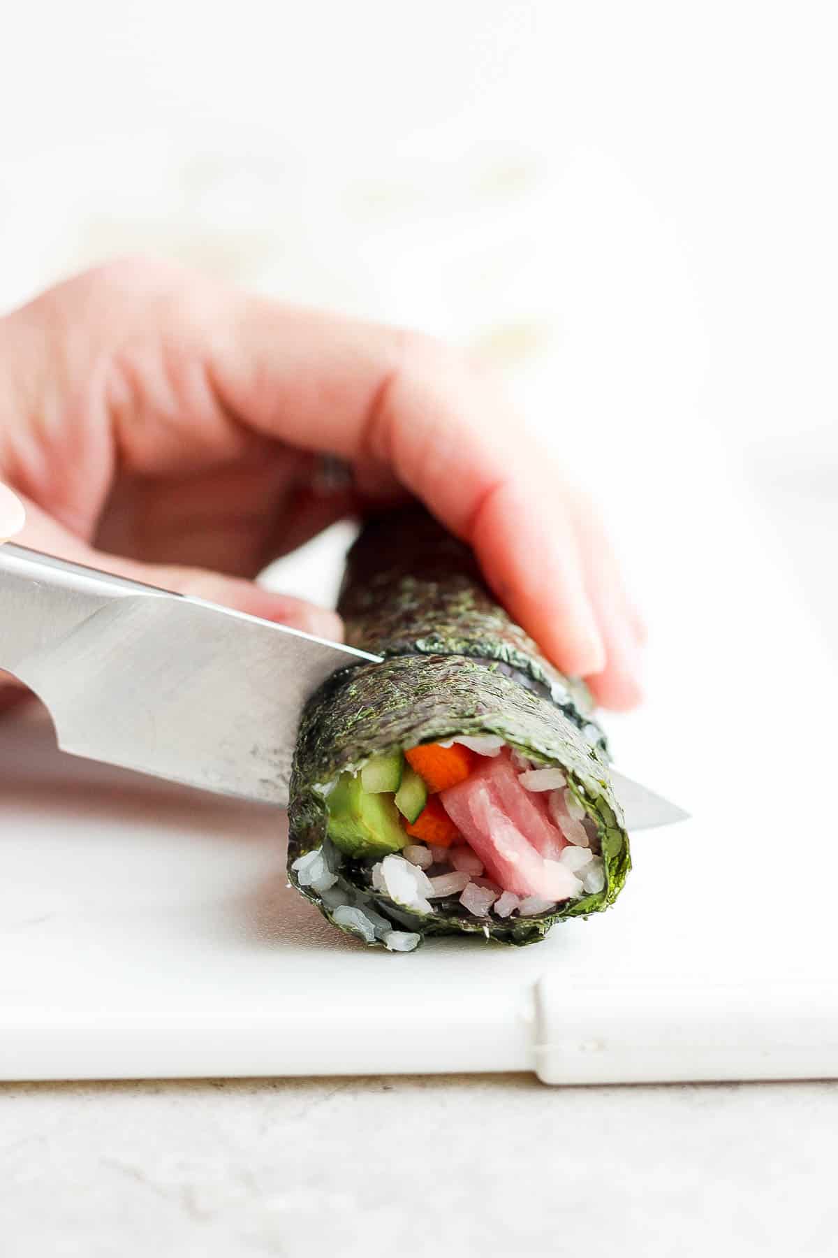 A sharp knife cutting the sushi roll into pieces.