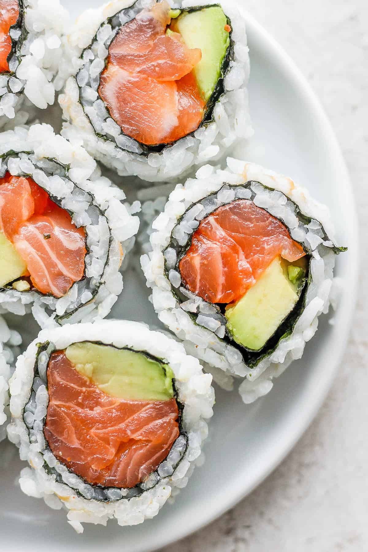 Pieces of a salmon sushi roll on a plate.
