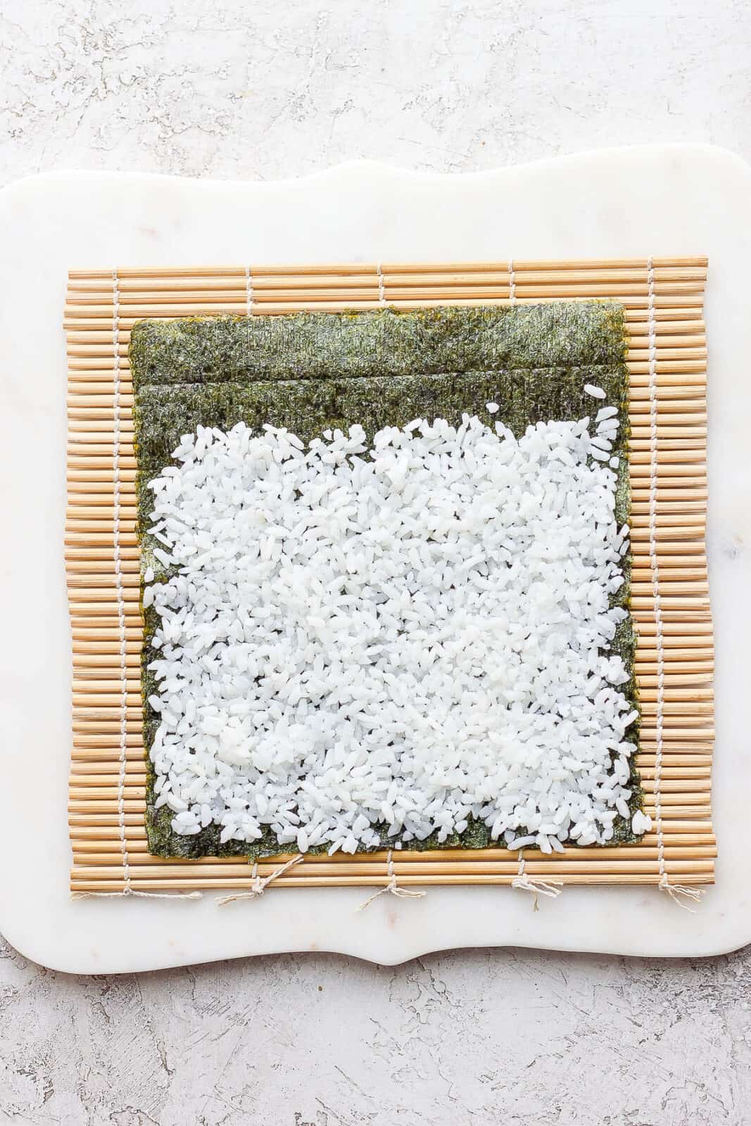 A thin layer of rice spread on top of a nori sheet.