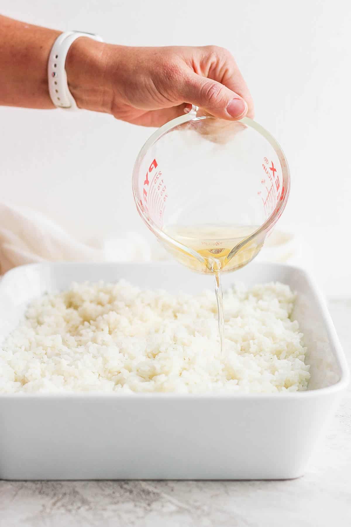 Sushi vinegar being poured on top of the cooked rice.