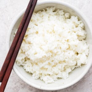 Bowl of Sushi Rice with chopsticks laying across.