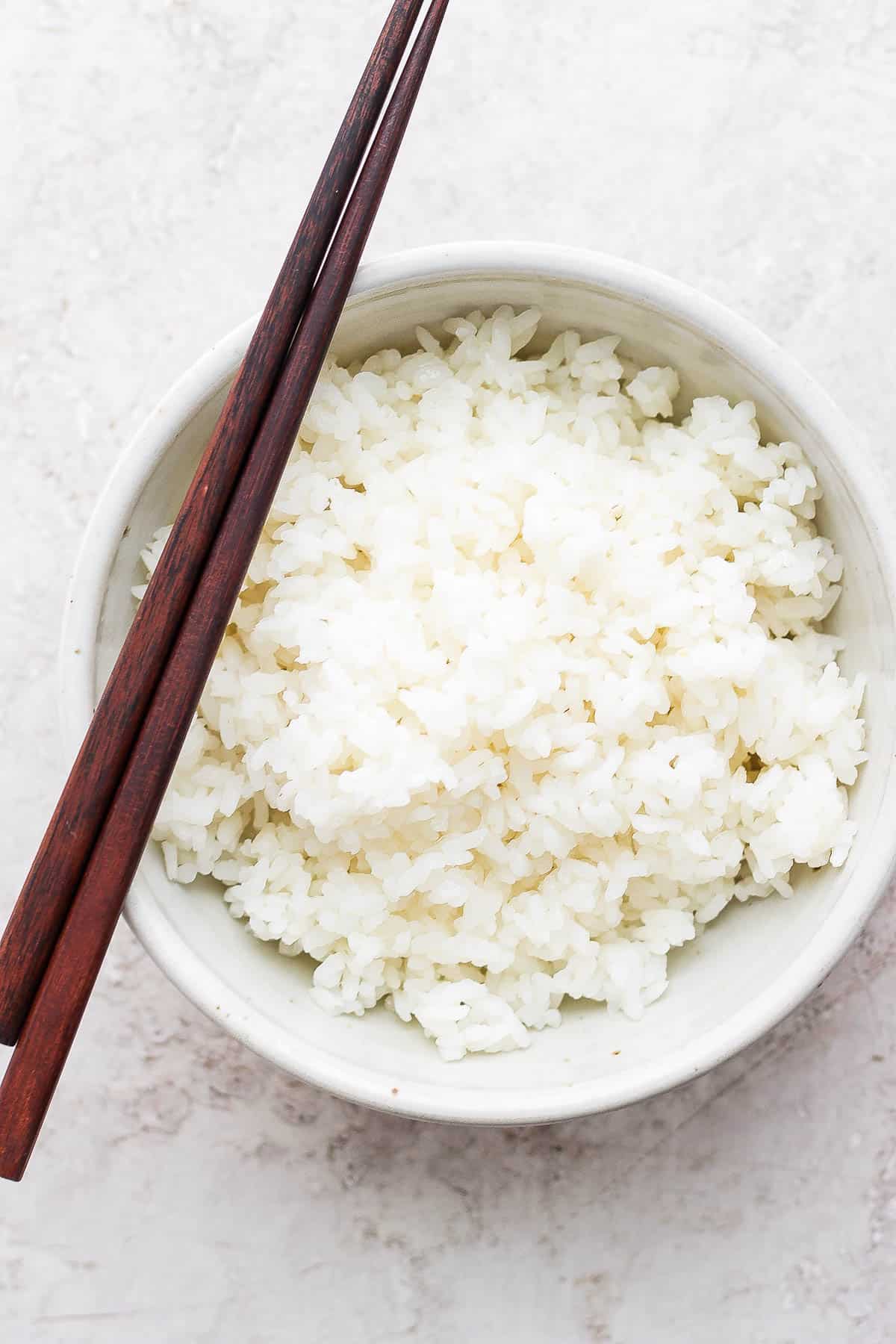 A bowl of sushi rice with chopsticks.