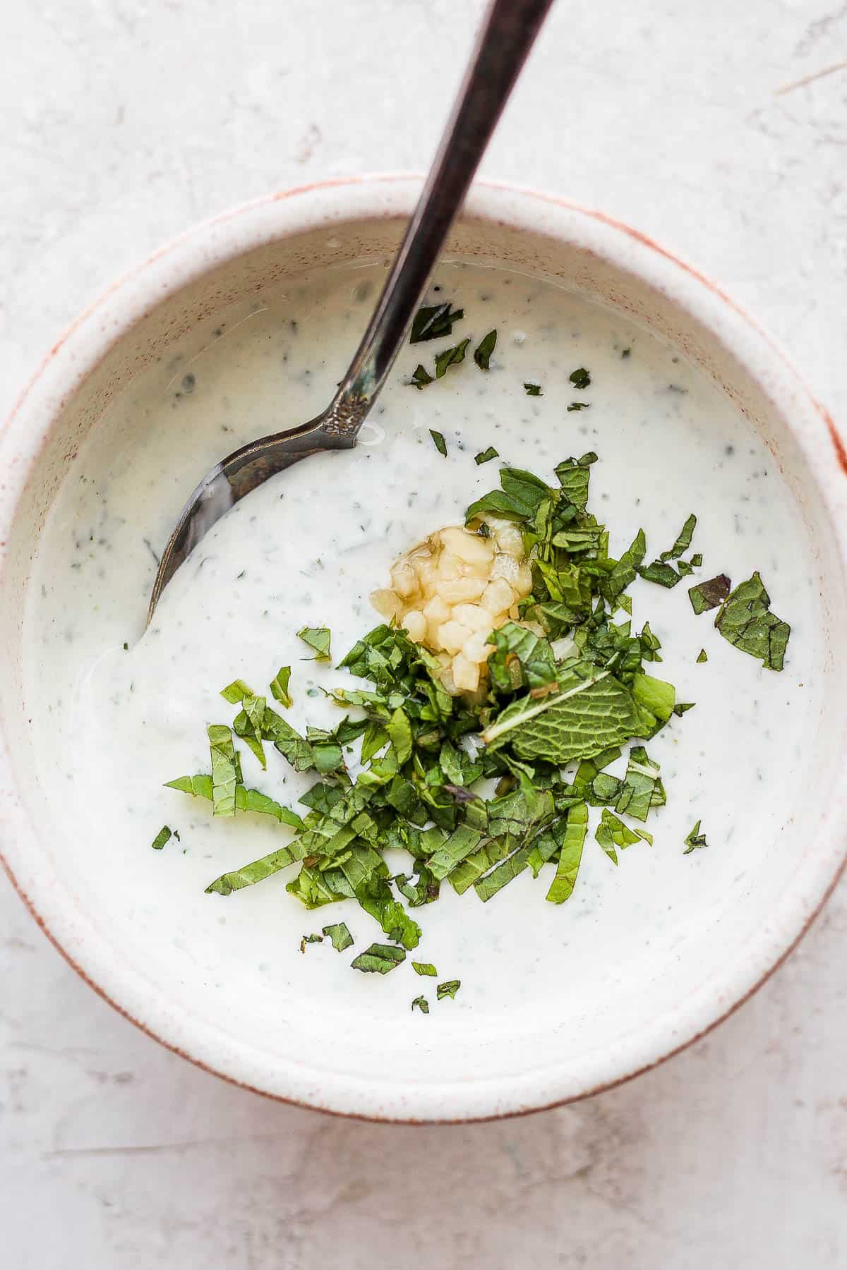 A bowl of lamb sauce garnished with fresh chopped mint and minced garlic. 